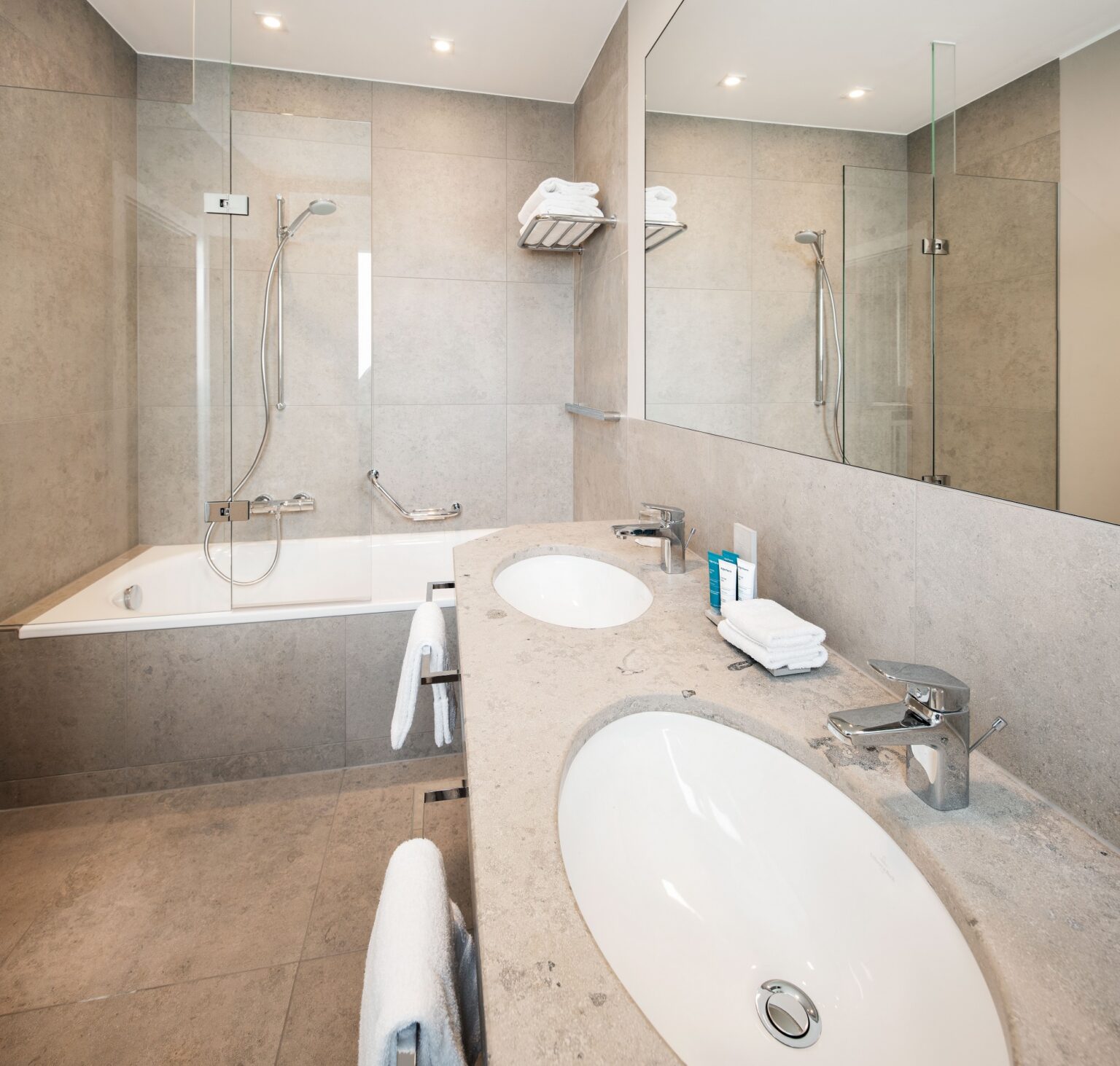 Badezimmer Suite aus hellem Naturstein, Doppelwaschbecken und Badewanne